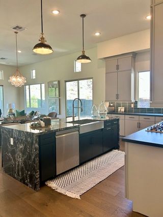 A modern kitchen with a black marble island, sleek cabinetry, and pendant lighting, offering a stylish cooking space.