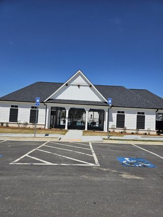 A charming white building with gabled roof and landscaped surroundings in Azalea Square Townhomes by Century Communities (Lawrenceville, GA).