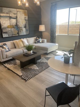 A modern living area featuring a cozy sectional, abstract art, and warm lighting, complemented by wood floors and chic decor.