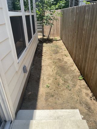 Model Home A side yard with a simple pathway and a small tree, enclosed with a wooden fence.