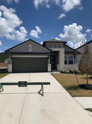 Street view A modern stone-accented home with a neat driveway in Lakeside at Tessera on Lake Travis by Saratoga Homes (Lago Vista, TX).