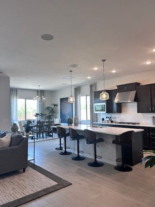 Model Home A modern open-concept kitchen and dining area with sleek dark cabinets, pendant lighting, and large windows.