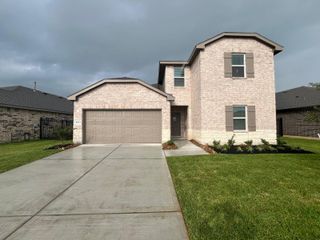 Street view A charming two-story brick home with neutral tones, a landscaped yard, and a two-car garage in Sunterra by D.R. Horton (Katy, TX).