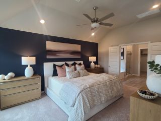 A cozy bedroom with a navy accent wall, modern ceiling fan, and soft lighting, featuring a spacious walk-in closet.
