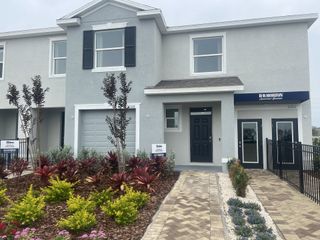 A modern townhouse with sleek lines and vibrant landscaping in Towns at Woodsdale by D.R. Horton (Wesley Chapel, FL).