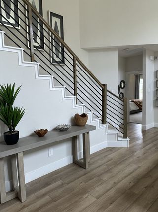 A modern entryway with sleek railings, light wood flooring, and decorative accents on a minimalist console table.