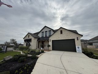 Street view Elegant stone house with modern features and landscaped yard in Crescent Bluff by GFO Home (Georgetown, TX).