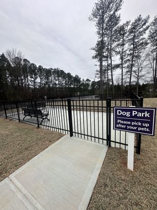 A welcoming dog park surrounded by tall trees in Azalea Square Townhomes by Century Communities (Lawrenceville, GA).