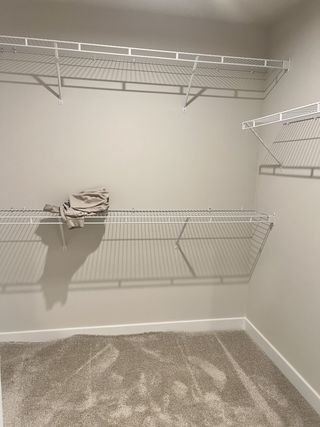 A spacious walk-in closet with plush carpet and organized wire shelving, perfect for storage efficiency.