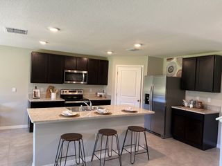 A modern kitchen with dark cabinetry, stainless steel appliances, and a spacious island.
