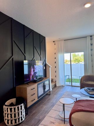 A modern living room with a textured black accent wall, sleek media console, and bright natural light from glass sliding doors.