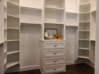 A spacious walk-in closet with white shelving, a central dresser, and elegant accents for a modern, organized feel.