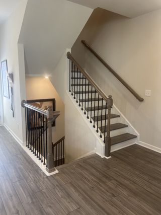 A modern staircase features elegant wood flooring and sleek railing design, enhancing a contemporary home atmosphere.