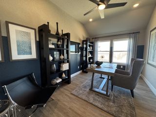 A modern home office with sleek shelving, stylish decor, a wooden desk, and large windows for natural light.