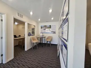 A modern office space with a small table, beige chairs, and detailed wall displays in a professional setting.