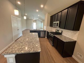A sleek kitchen with granite countertops, dark cabinets, stainless steel appliances, and a spacious open layout.