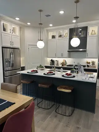 A modern kitchen with pendant lighting, sleek appliances, a spacious island with seating, and elegant cabinetry.