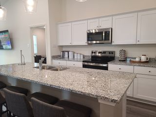 Model Home A modern kitchen with granite countertops, sleek stainless steel appliances, and elegant pendant lighting.