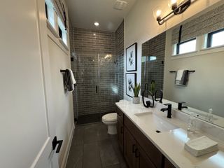Model Home A stylish bathroom with elegant gray subway tiles, a sleek vanity, black fixtures, and modern lighting.