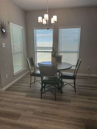 Model Home A cozy dining area with a round table, elegant chandelier, and large windows enhancing natural light.