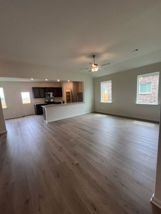 An open living space with sleek hardwood floors, recessed lighting, and a modern kitchen, perfect for gatherings.