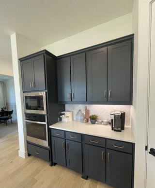 A sleek kitchen nook with dark cabinetry, gold hardware, and white countertops in Solterra Texas by Shaddock Homes (Mesquite, TX).