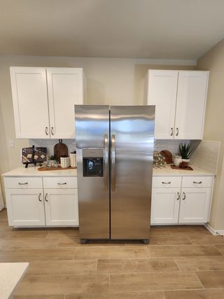 A modern kitchen with sleek stainless steel appliances, white cabinetry, and wood flooring.