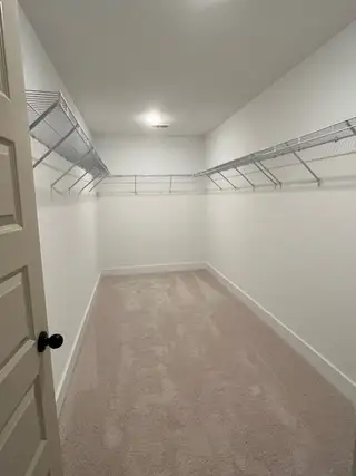 A spacious walk-in closet with plush carpeting and ample wire shelving for organized storage.