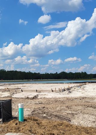 Street view A scenic view of a construction site near a serene lake in Westview: Aden South I by Lennar, Kissimmee, FL.