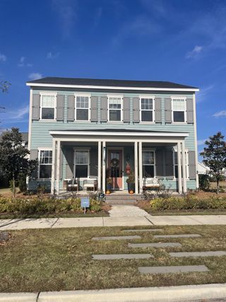 A charming two-story blue home with gray shutters and a cozy porch in Midtown at Nexton by Ashton Woods (Summerville, SC).