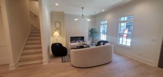 A cozy living room with a sleek fireplace, plush seating, a modern lamp, and hardwood floors.