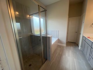 Modern bathroom featuring a glass-enclosed shower, a sleek bathtub, and elegant floor tiles.