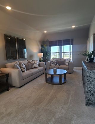 Model Home A cozy living room with plush sofas, neutral tones, elegant décor, and large windows bringing in natural light.