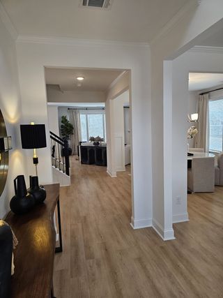 Model Home A bright and inviting hallway with light wood flooring, high ceilings, and a stylish entry table.