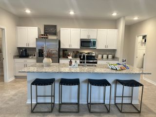 A contemporary kitchen with granite countertops, sleek appliances, and a stylish island featuring chic black stools.