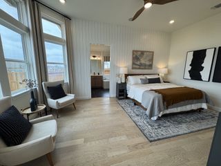 A warm and inviting bedroom with wood flooring, accent walls, and cozy textures in Veramendi by Brightland Homes (New Braunfels, TX).