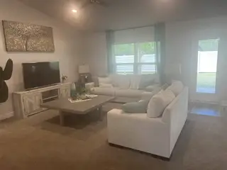 A cozy living room with plush sofas, neutral tones, a stylish coffee table, and a large TV for relaxing evenings.