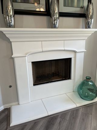 Model Home A chic interior fireplace with a sleek white mantel, decorative accents, and elegant flooring.