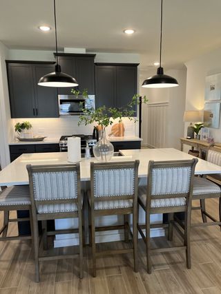A modern kitchen with sleek black cabinets, a white countertop island, and stylish pendant lighting.