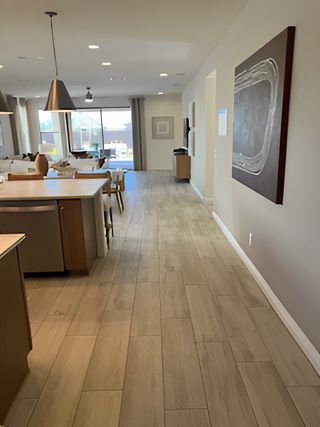 A modern open-concept living area with wood-look flooring, chic lighting, and large windows connecting to outdoor views.
