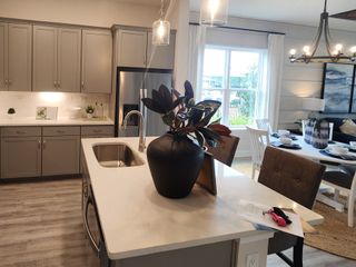A modern kitchen with sleek gray cabinets, stainless steel appliances, and an open floor plan leading to a cozy living space with lake views.