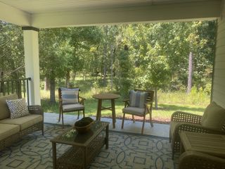 Model Home A cozy patio with wicker furniture and a serene view of lush green trees, offering a peaceful retreat.