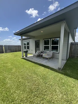 A cozy patio with seating on a lush lawn in Laurel Farms by Century Communities (Brookshire, TX).