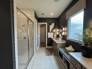 A modern bathroom with a glass shower, dual vanities, black accents, and elegant lighting.
