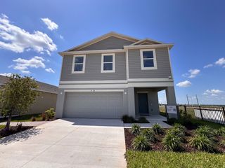 A modern gray two-story home with a neat driveway and lawn in Scenic Terrace by Taylor Morrison (Lake Hamilton, FL).