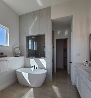 A modern bathroom featuring a freestanding tub, textured wall tiles, and sleek cabinetry.