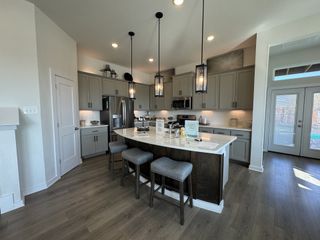 A modern kitchen with a central island, sleek gray cabinets, and pendant lighting, featuring stainless steel appliances.
