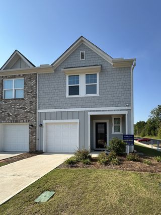 A charming grey townhouse with a landscaped yard in Greyson Parc by Starlight Homes (Locust Grove, GA).