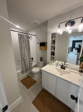 A stylish bathroom featuring a white vanity, black fixtures, and a subway-tiled bathtub with a bold striped shower curtain.