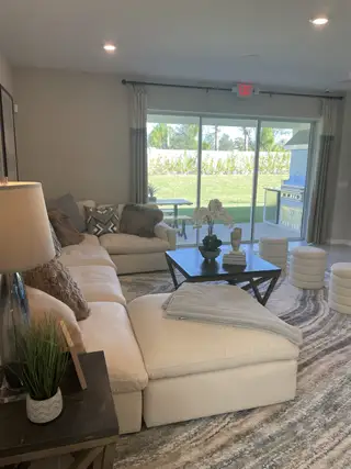 A cozy living room featuring a plush sectional, modern coffee table, and large window with outdoor views.